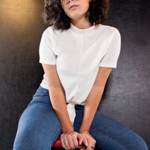 Fashionable woman with eyewear posing confidently indoors in denim jeans.