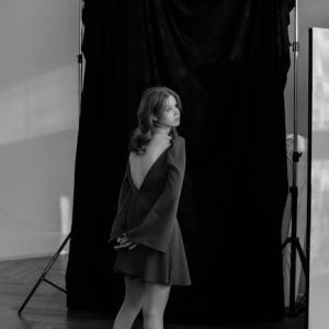 Black and white portrait of a woman in a studio setting, barefoot and posed elegantly.